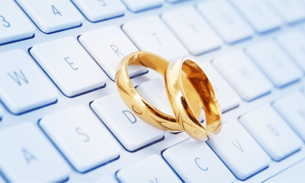Latest UAE Updates How to get married online | Latest UAE Update: How to get married online | This is because this post includes a brand-new and entirely legal method for learning how to get married online. Furthermore, you will not be required to travel anyplace in order to complete it. Continue reading to learn how to locate a marriage that doesn't require you to travel. The image features two shiny gold wedding rings resting on a white computer keyboard, suggesting a blend of tradition and technology. The keys visible include letters such as W, E, D, and S which highlight themes of weddings. The bright background enhances the elegance of the rings while showcasing the digital connection to modern marriage processes.