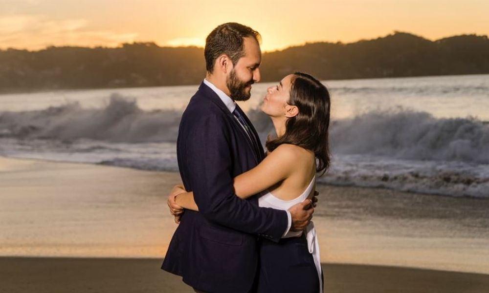 Top Countries For Foreigners To Get Married Easily | Top 5 Wedding Destinations For Foreigners To Get Married Easily | If You Are Planning On Getting Married This Year; Here'S Our Top Picks Of Countries Where Foreigners Can Get Married Easily. A happy couple embraces on a beautiful beach at sunset with gentle ocean waves and a golden sky behind them. The man wears a sleek dark suit while the woman shines in her elegant white dress. Their joyful smiles radiate love as they celebrate their special moment together in this romantic atmosphere filled with warmth and peace.