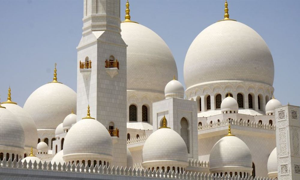 What Does Abu Dhabis New Non Muslim Law Entail 72Afcc11 | What Does Abu Dhabi'S New Non-Muslim Law Entail? | The New Law In Abu Dhabi — The First Civil Law In The Emirates Dealing With Non-Muslim Family Problems — Is A Real Game Changer For The Uae'S Talent Acquisition. For A Very Simple Reason Because Just Like The Uae; Abu Dhabi Is The 2Nd Largest Home To Expats From Around The World. The image shows the Sheikh Zayed Grand Mosque in Abu Dhabi, featuring large white domes adorned with gold accents. The mosque's exquisite architecture creates a serene and majestic setting ideal for weddings. Clear blue skies highlight the beauty of this iconic structure, symbolizing tranquility and culture.