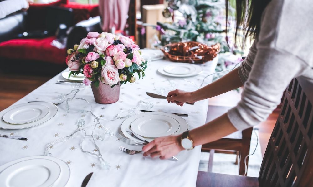 A beautifully arranged dining table showcases an inviting setup with white linens and pink flowers. The scene captures a warm atmosphere perfect for weddings or celebrations, complete with silverware and soft lighting to enhance the charm of your event.
