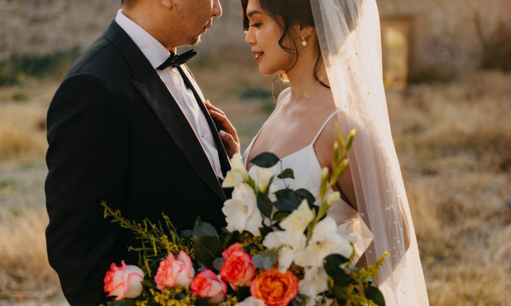 768A1418 1 scaled 19623524 | Philippines Divorce Guide 2024: Understanding New Laws and Solutions | Are you wondering why Philippines divorce is still illegal and what might be changing? The image features a joyful bride holding a colorful bouquet of flowers beside her groom in a black tuxedo. They are surrounded by warm golden lighting that enhances the romantic vibe of their outdoor wedding setting. The couple looks deeply into each other's eyes showcasing love and happiness. Historical stone walls can be seen in the background creating a fairy-tale ambiance capturing the spirit of their special day.