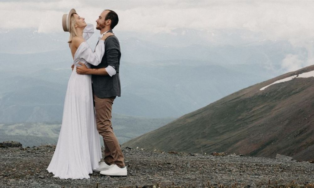 A joyful couple smiling at each other during their wedding ceremony in an elegant venue in Dubai. The background shows beautifully arranged flowers and an intimate setting perfect for celebrating love, capturing a moment filled with happiness and togetherness as they begin their life journey together.