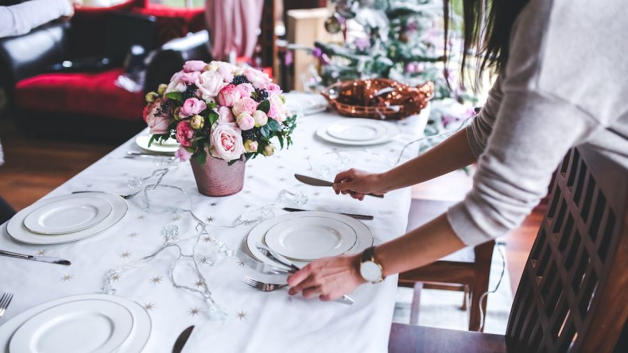 A beautifully arranged dining table showcases an inviting setup with white linens and pink flowers. The scene captures a warm atmosphere perfect for weddings or celebrations, complete with silverware and soft lighting to enhance the charm of your event.