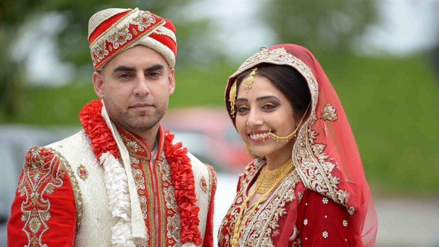 A couple sitting together at an outdoor wedding ceremony in Dubai. They appear happy and relaxed as they celebrate their love with vibrant scenery in the background. The scene captures the essence of a joyful wedding day surrounded by family and friends, showcasing decorations typical of a luxurious event in Dubai.