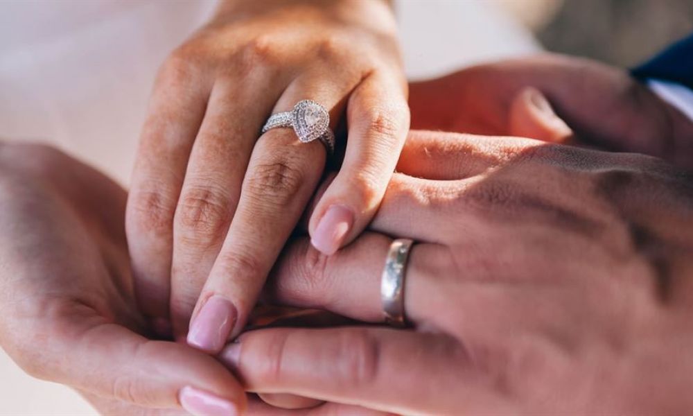 a sparkling diamond ring rests on a hand beside a classic wedding band in soft lighting to symbolize love and unity captured beautifully together.