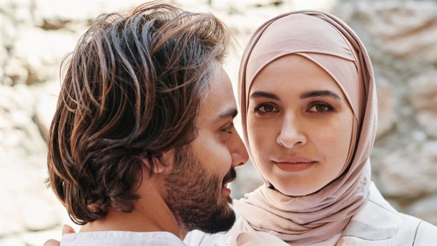 A happy couple smiling together as they plan their wedding in Dubai surrounded by stunning scenery and decorations, showcasing love and excitement for their special day. They are exploring various options like civil marriage and online registration while enjoying the outdoor atmosphere typical of Dubai events.