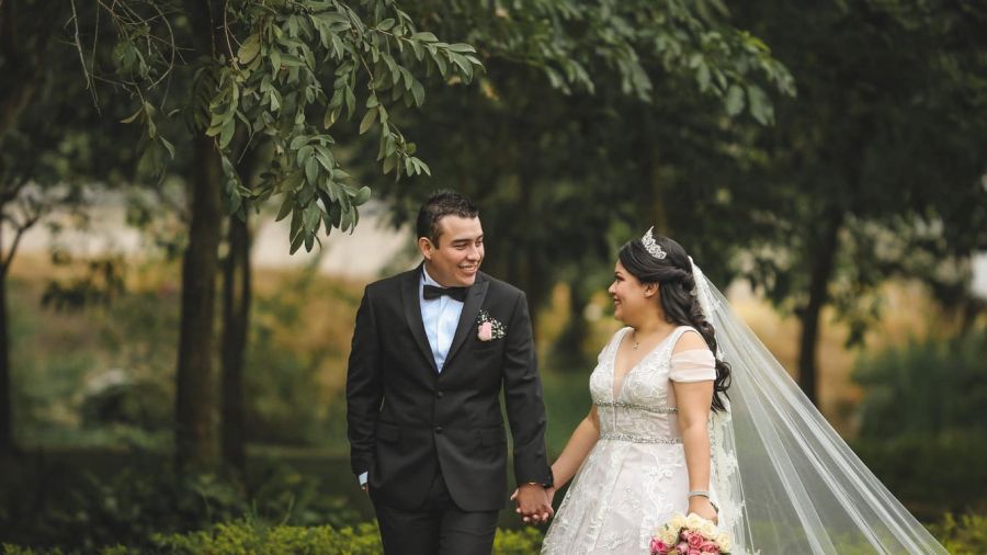 A beautiful image of a joyous couple celebrating their wedding day against the stunning backdrop of Dubai's skyline. They are surrounded by flowers and smiling guests as they exchange vows. The scene radiates happiness and love on this special occasion, showcasing elegant decorations that enhance the festive atmosphere. The couple looks blissfully happy in their wedding attire, embodying the dream wedding many aspire to have in UAE.