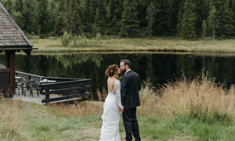 Packages to plan a dream wedding in UAE f875834b | Packages to plan a dream wedding in UAE | Weddings serve as the official start of your enduring love story and are proof positive that your aspirations of spending the rest of your life with your ideal spouse have come true. The trick to making it as really unforgettable as possible is planning to have all the necessities on hand. Georgia, on the contrary side, offers everything you could possibly need, including the arrangements for the romantic wedding you have in mind to live up to all of your dreams, at the most affordable budget and in breathtaking surroundings. This article compares packages to plan a dream wedding in UAE and Georgia. UAE is one of the GCC countries that accepts reservations and yet has long wait times and expensive spring, summer, or fall weather. A happy couple stands by a serene lake, dressed in beautiful wedding attire. The bride is in a lovely white gown while the groom wears a sleek suit. They seem to be enjoying each other’s company surrounded by lush greenery and trees, creating a romantic atmosphere that captures the joy of love and celebration during their wedding ceremony.